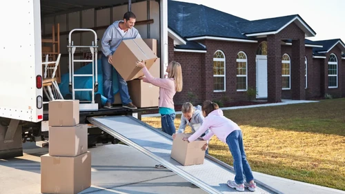 Family passing boxes down an assembly line from a moving truck